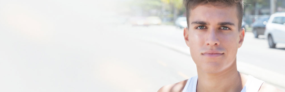 Young male in tank top standing on a street sidewalk