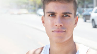 Young man standing on a sidewalk.