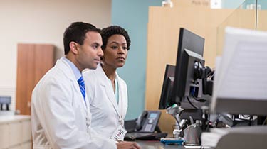 Two medical professionals looking at a computer monitor together