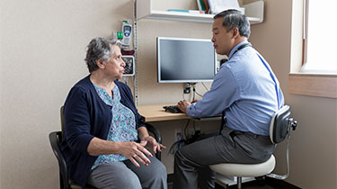 Doctor talking with his female senior patient in the exam room