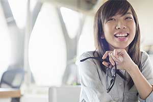 Woman sitting and smiling and holding her glasses